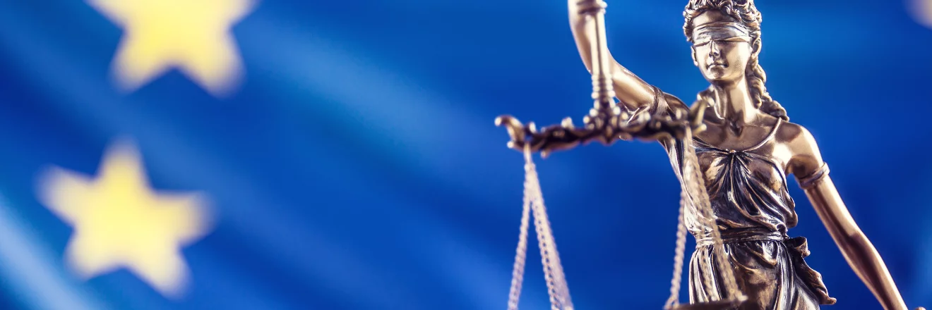 Justitia, die römische Göttin der Gerechtigkeit, vor einer EU-Flagge